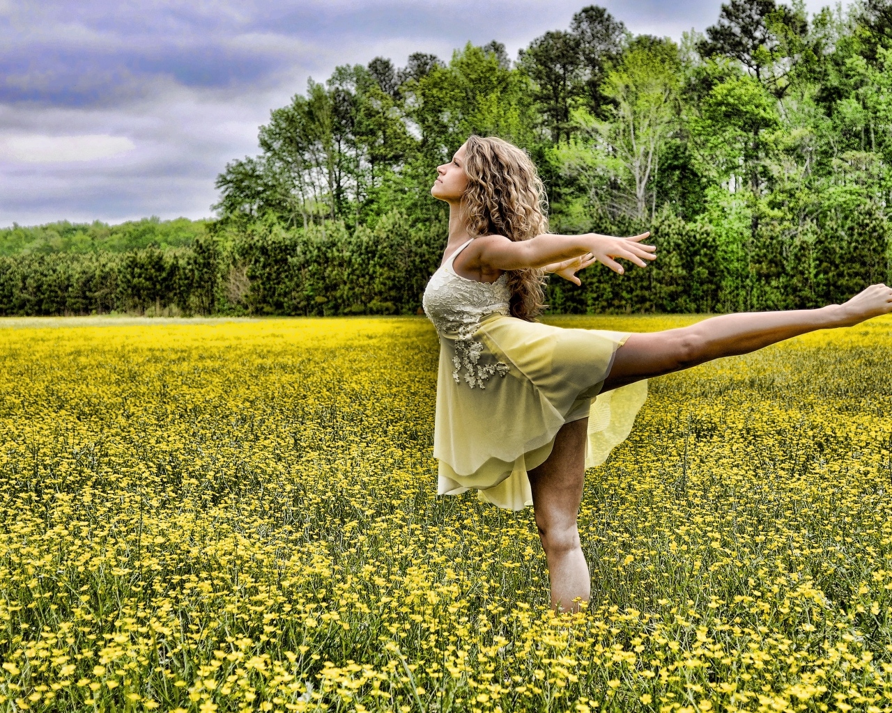 Девушка танцует на поле с желтыми цветами