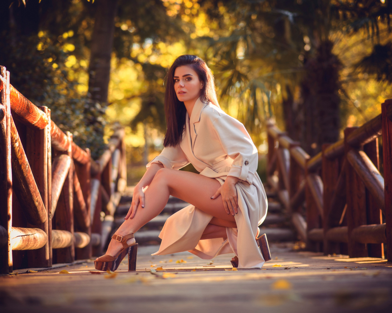 Девушка в пальто на мосту в парке 