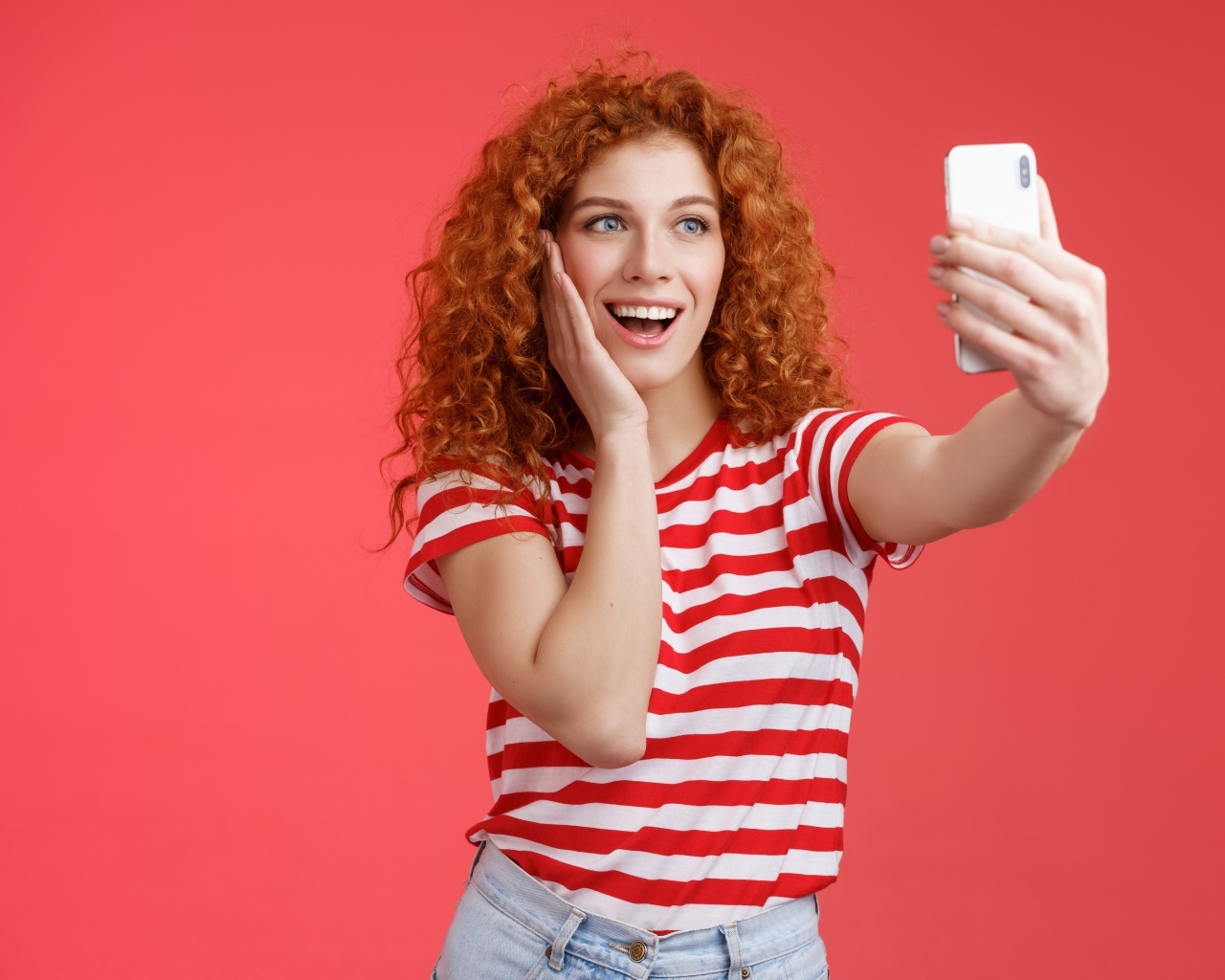 Девушка делает селфи на красном фоне