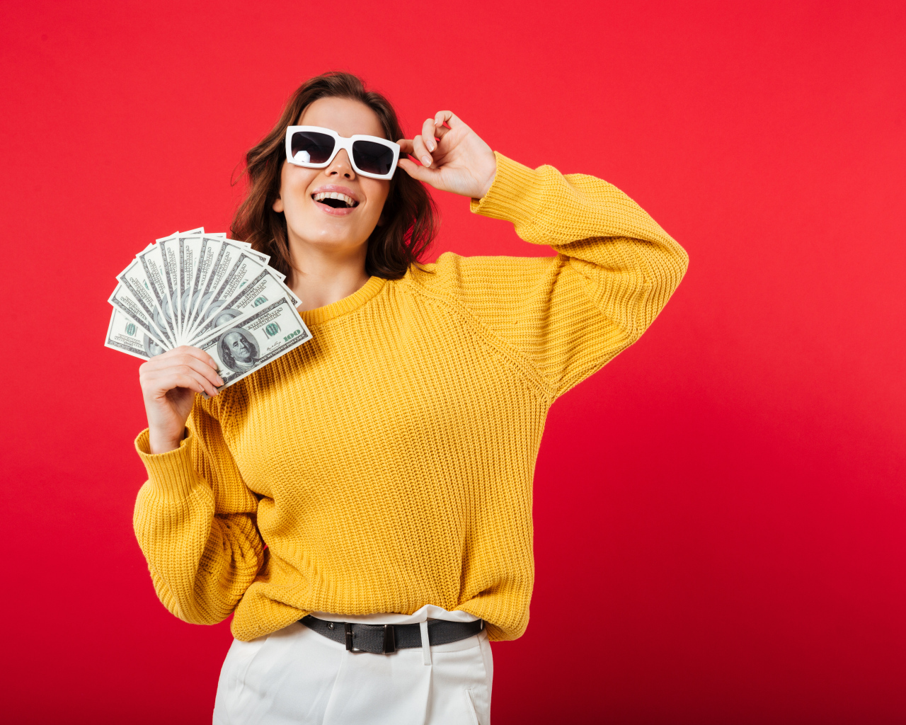 Девушка с веером из долларов на красном фоне