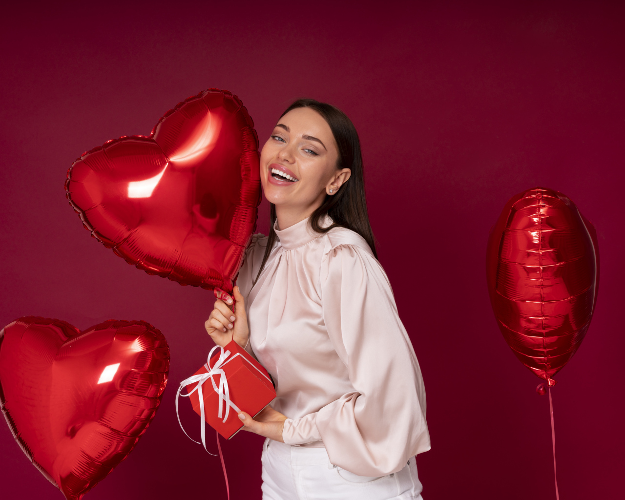 Девушка с шарами в форме сердца на красном фоне