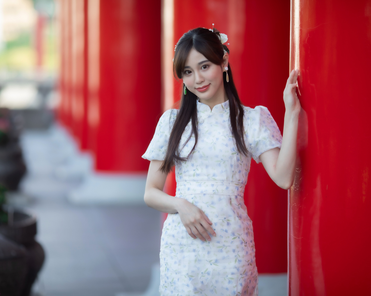 Длинноволосая азиатка позирует у красной колонны