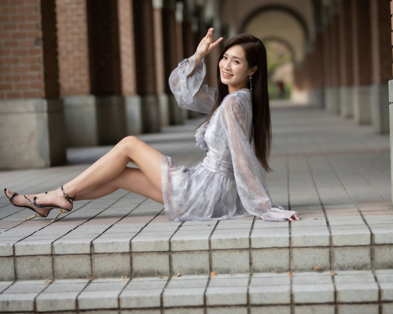 Улыбающаяся девушка азиатка сидит у ступеней
