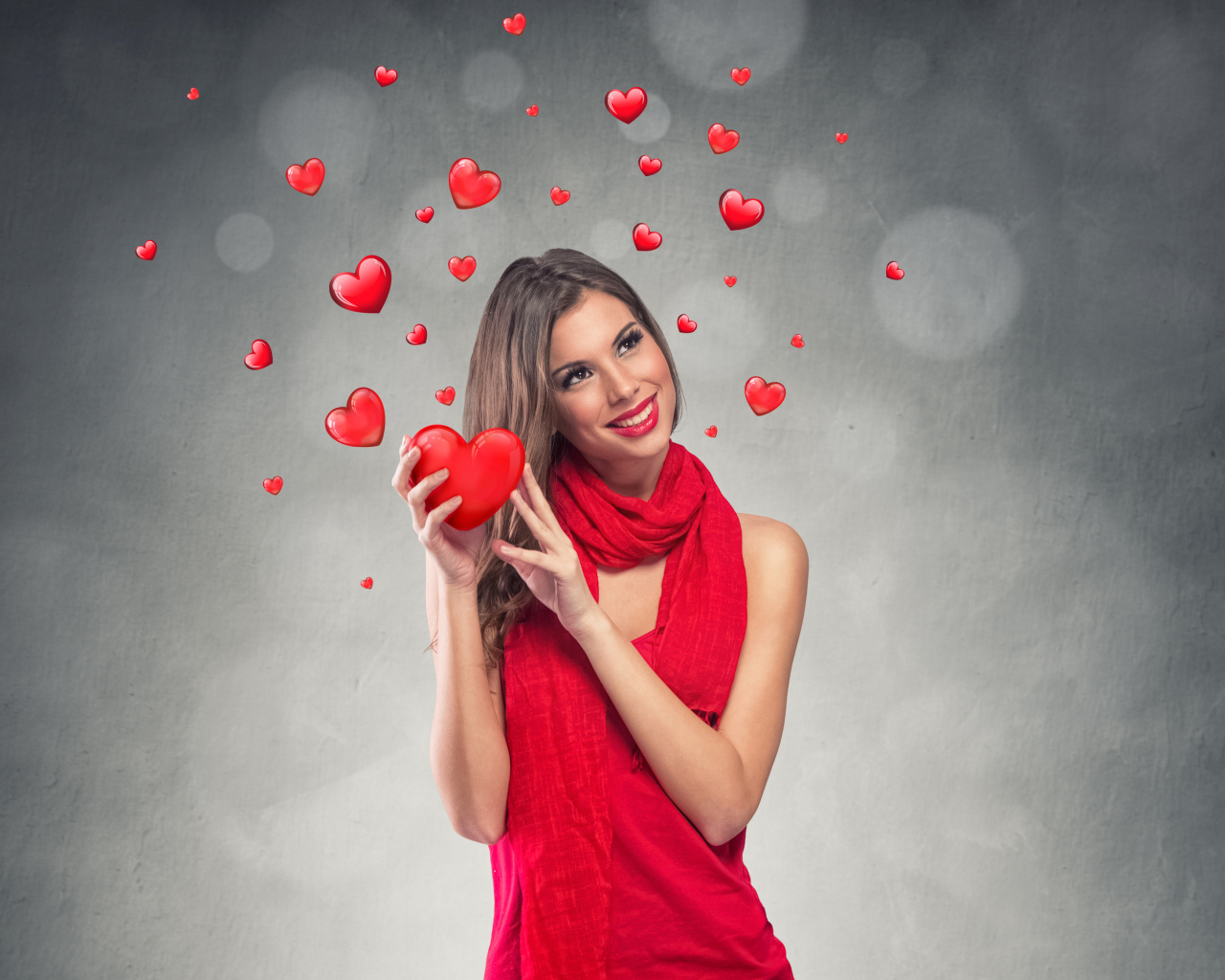 Улыбающаяся девушка в красном платье с сердечками на сером фоне