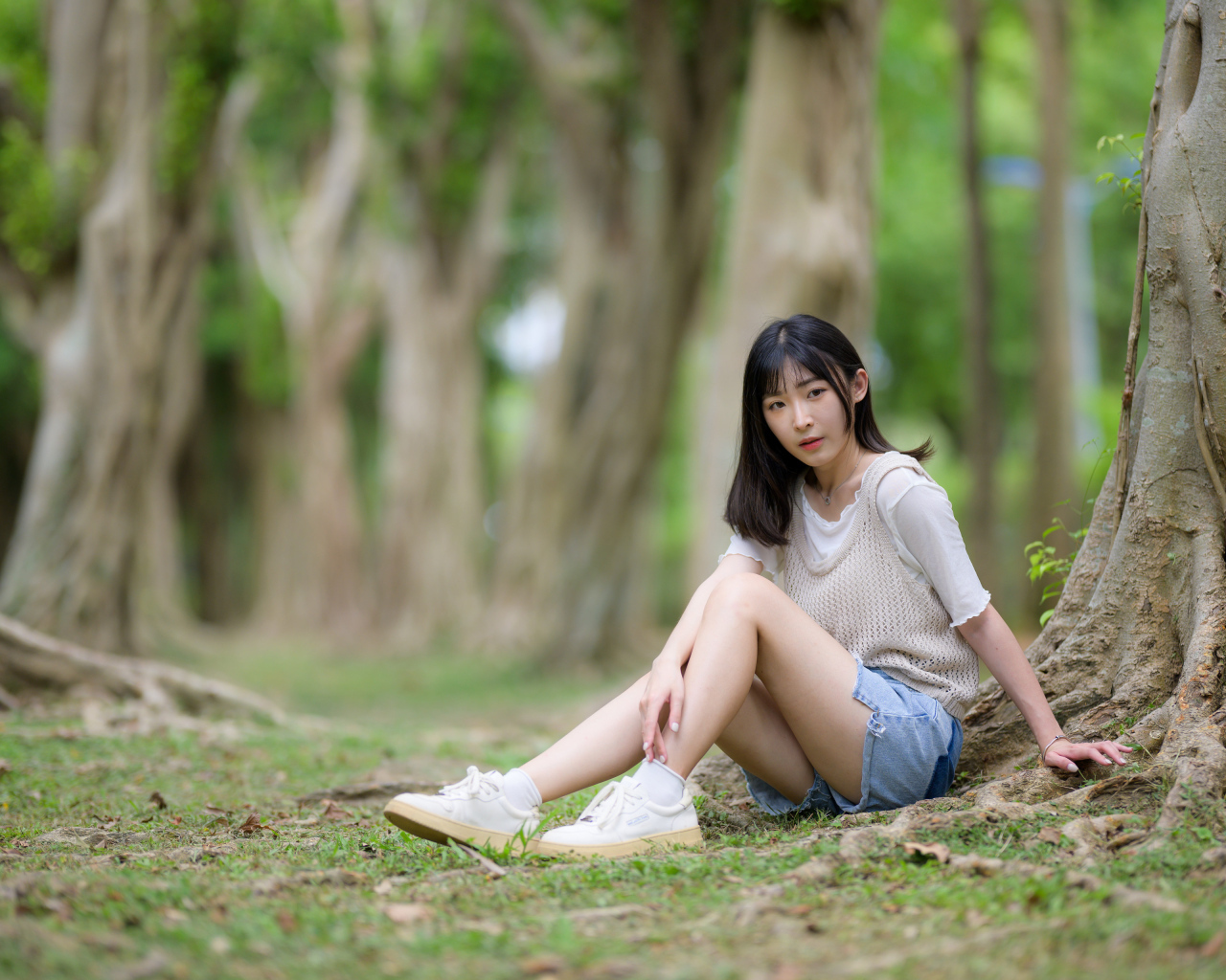 Молодая девушка азиатка сидит у дерева в парке