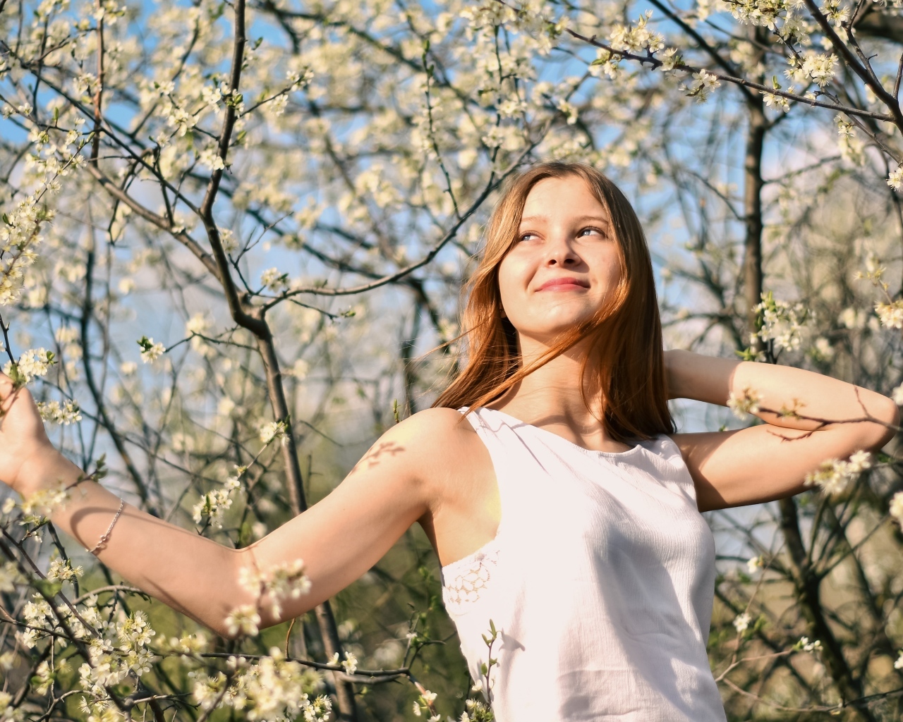 Молодая девушка у цветущего дерева весной