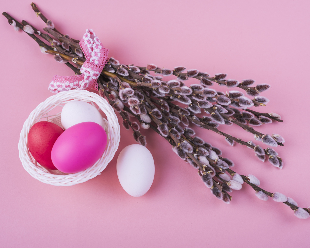 Ветки вербы с яйцами на розовом фоне