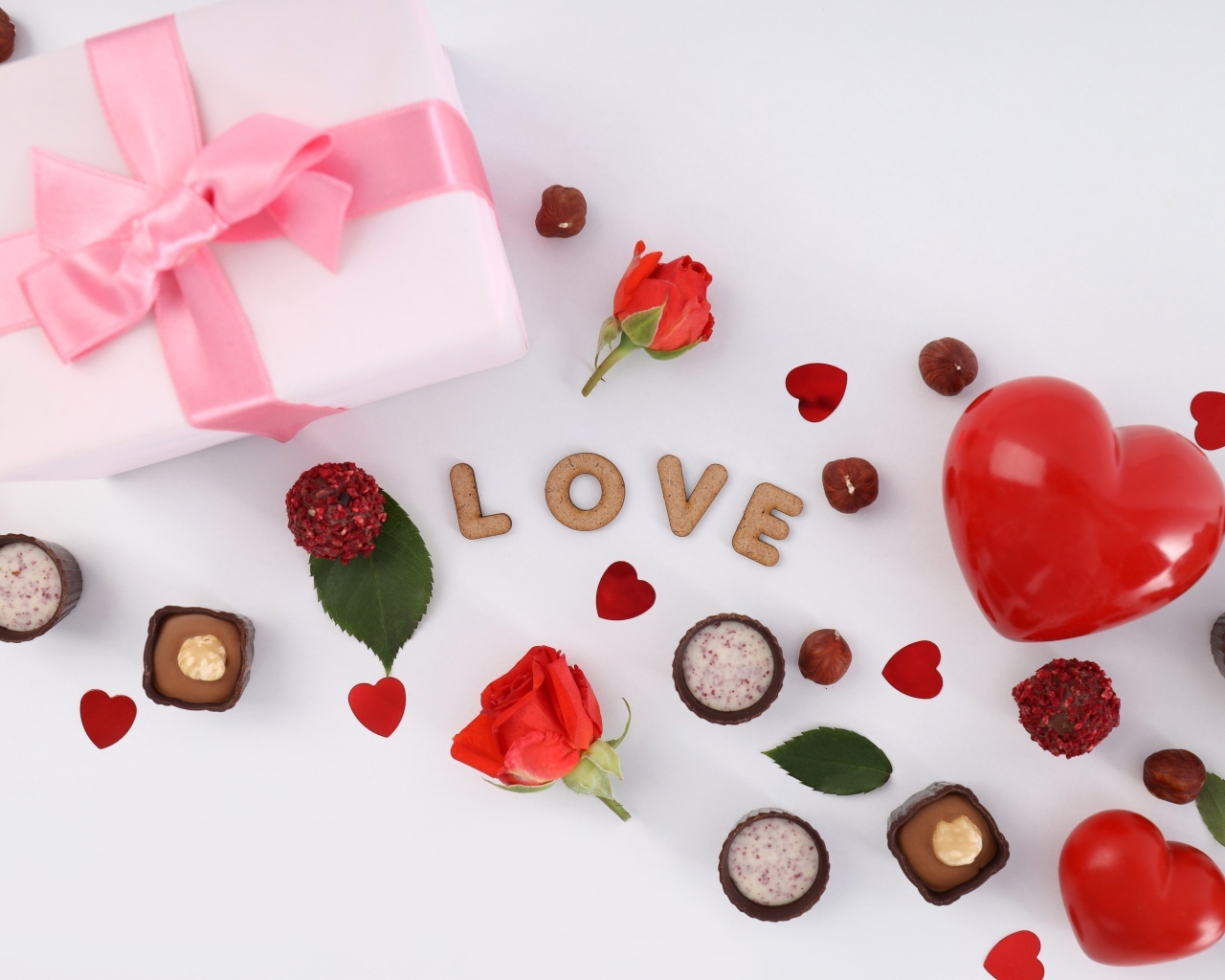 Подарок и сердечки с конфетами на столе на День Святого Валентина