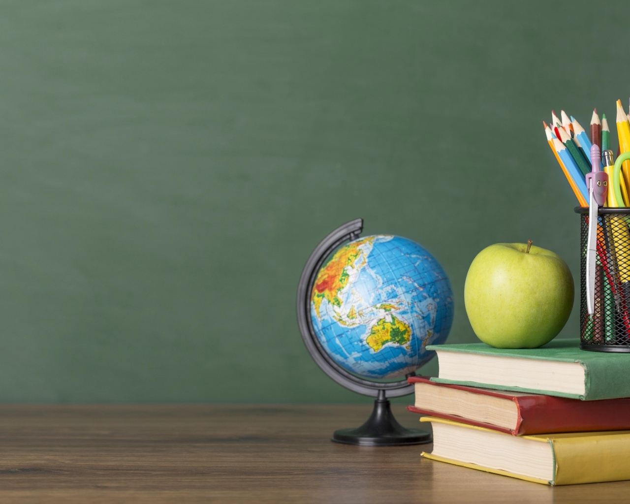 Книги на столе с глобусом, яблоком и ручками в школе