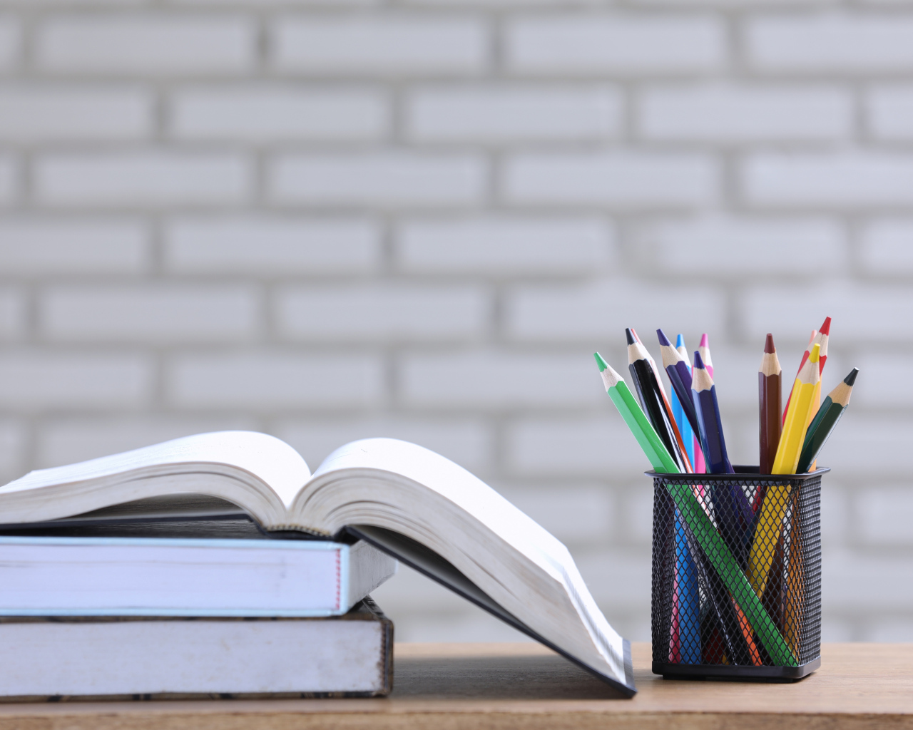 Разноцветные карандаши на столе с книгами 