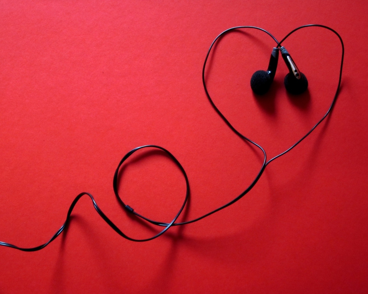 Черные наушники в форме сердца на красном фоне