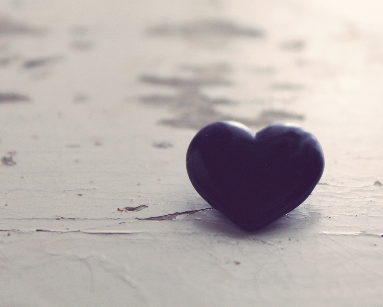 Черное каменное сердце на деревянной поверхности 