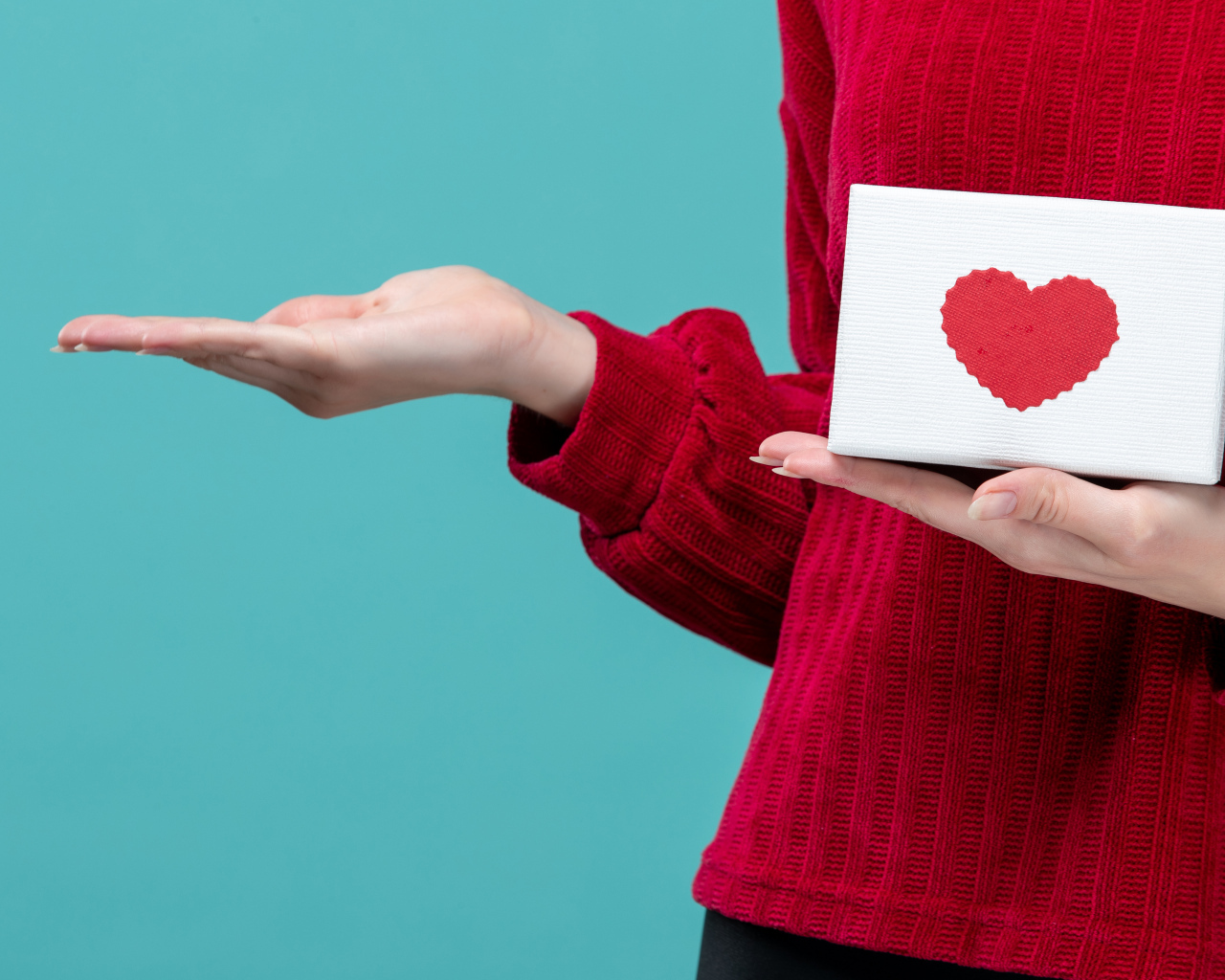 Коробка с сердцем в руке у девушки на голубом фоне
