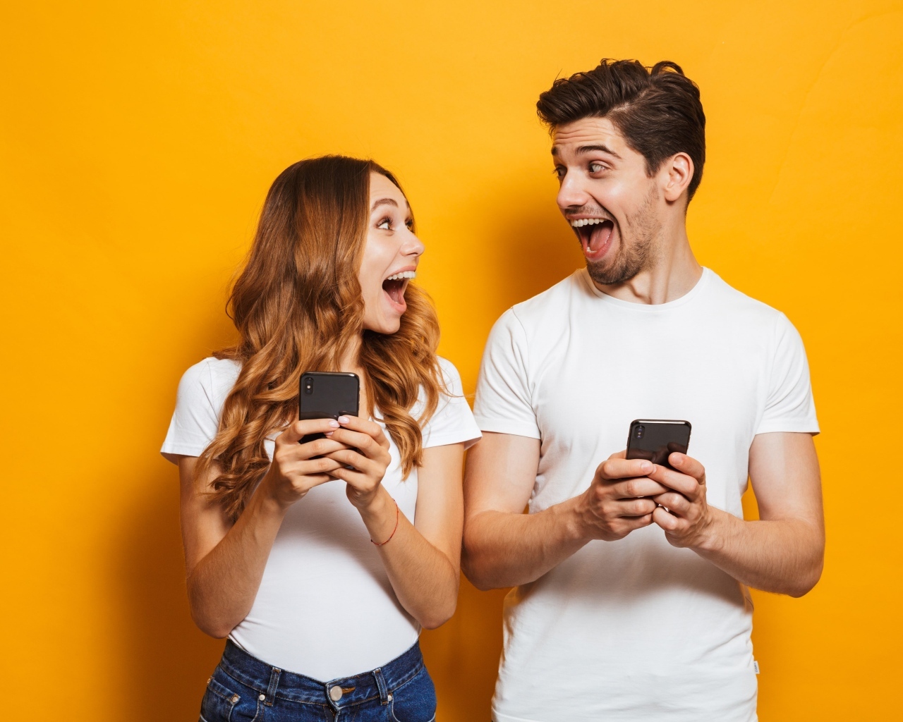 Счастливые парень и девушка с мобильными телефонами