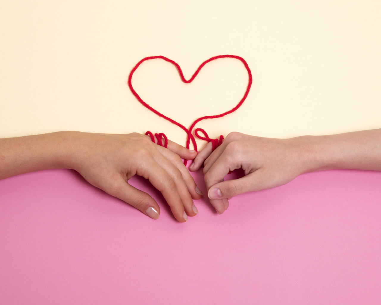 Человеческие руки связаны красной нитью в форме сердца
