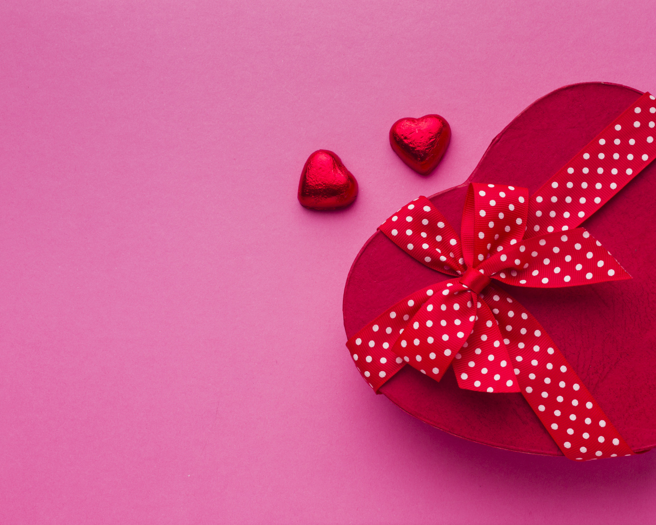 Большая красная коробка в форме сердца на розовом фоне
