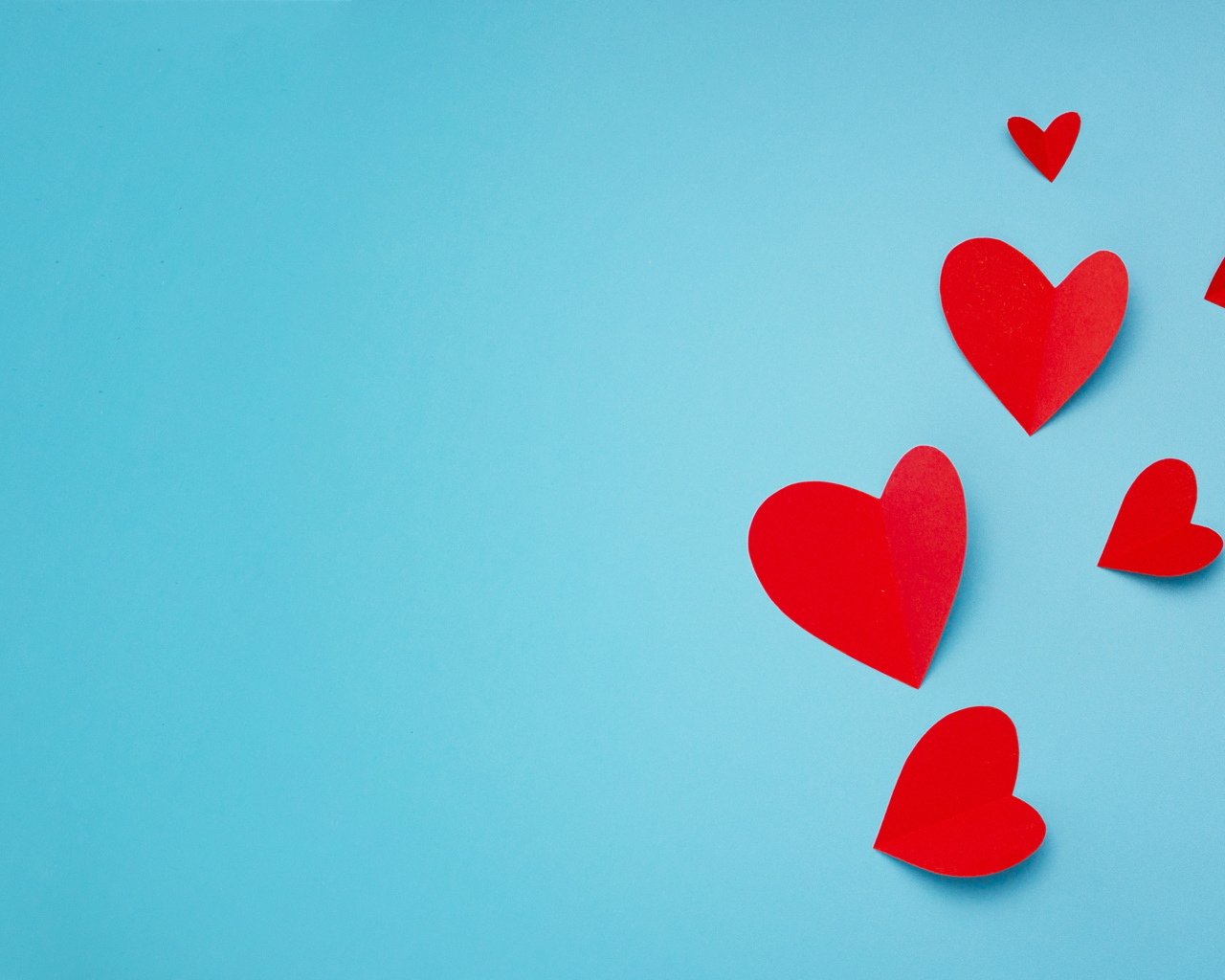 Много красных бумажных сердечек на голубом фоне