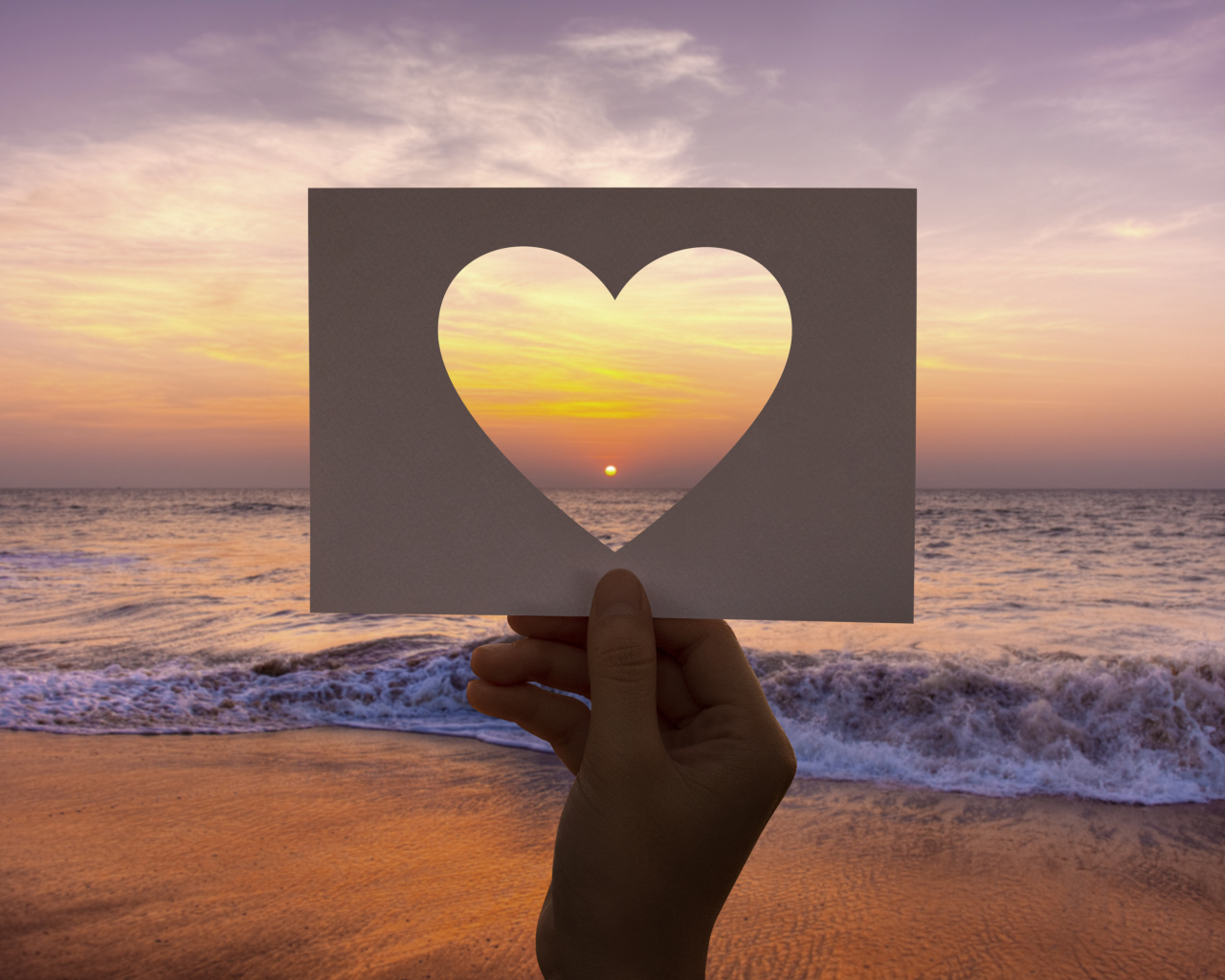 Бумажное сердце на фоне моря на закате солнца