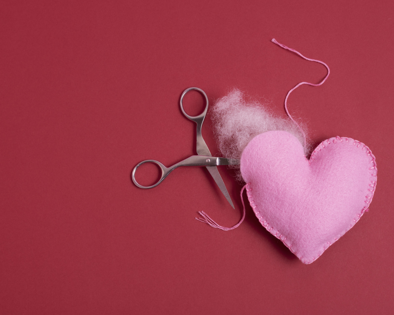 Розовое  сердце с ножницами на красном фоне