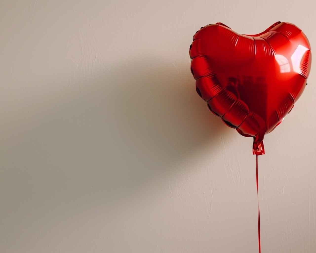 Красный шарик в форме сердца на сером фоне
