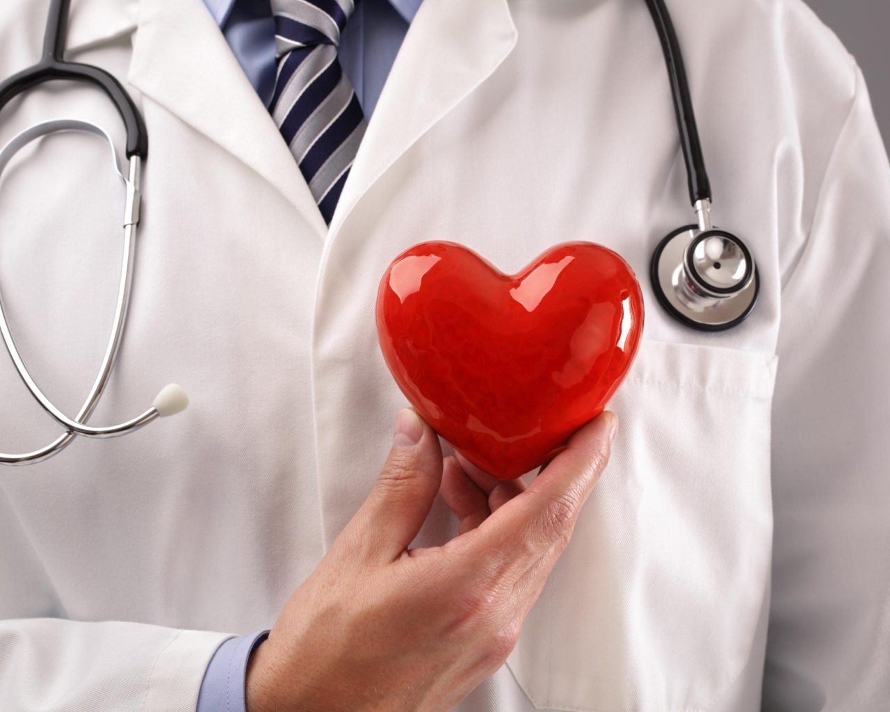 Красное сердце в руках доктора в белом халате