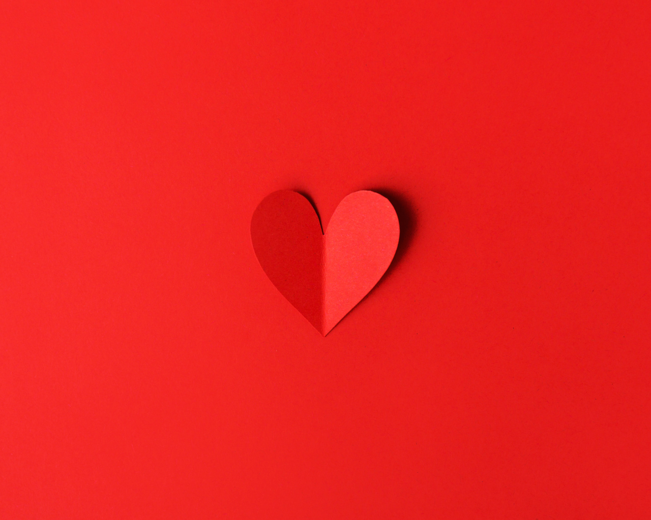 Маленькое бумажное сердце на красном фоне