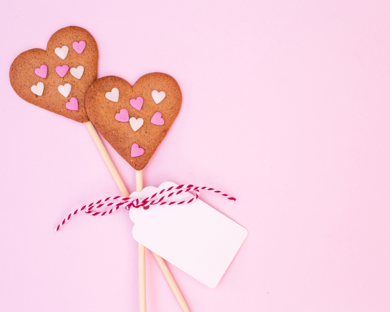 Два сердечка на палочке на розовом фоне