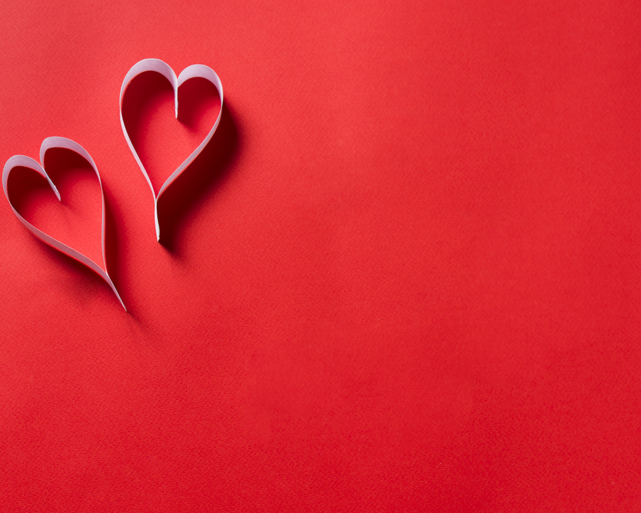 Два белых бумажных сердца на красном фоне