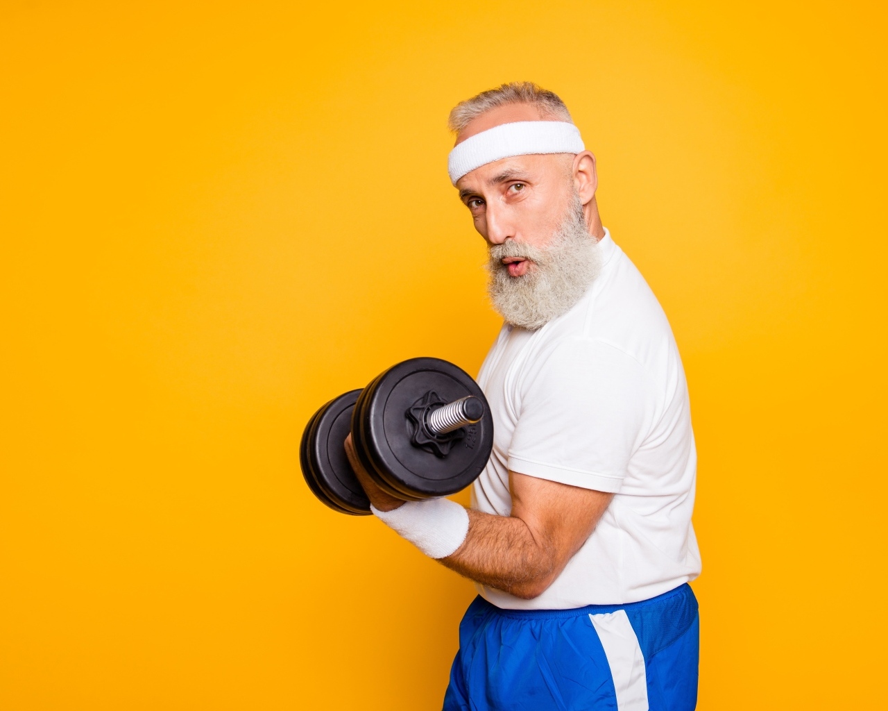 Спортивный мужчина с гантелей в руке на желтом фоне