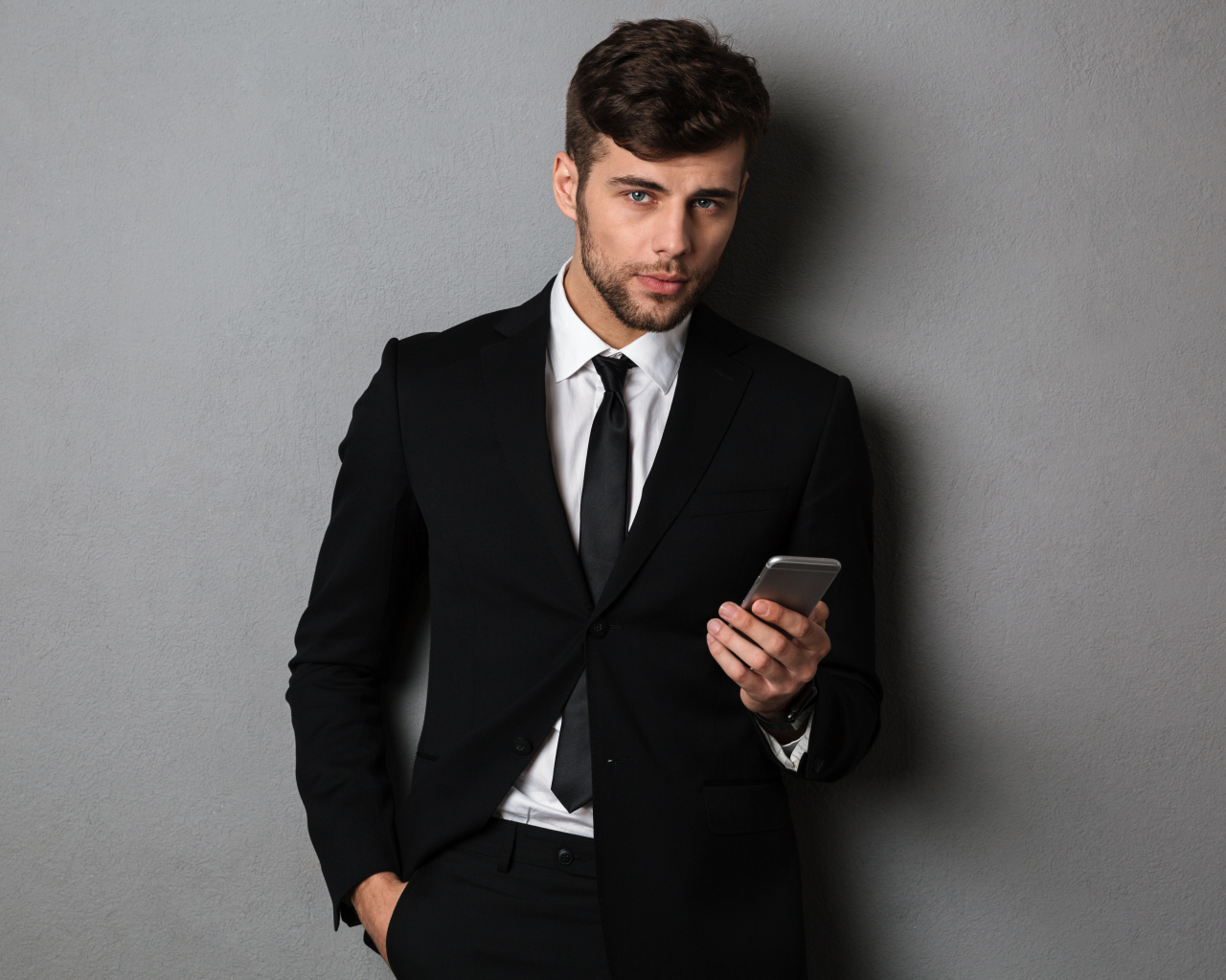 Деловой мужчина в костюме стоит у стены с телефоном