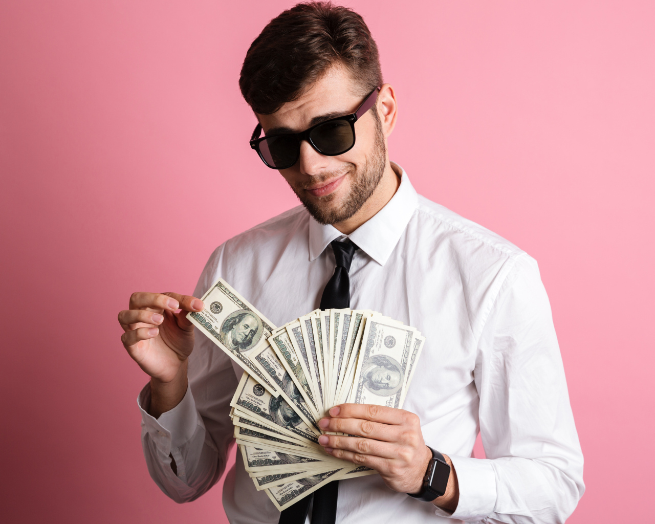 Деловой мужчина в черных очках с пачкой денег на розовом фоне