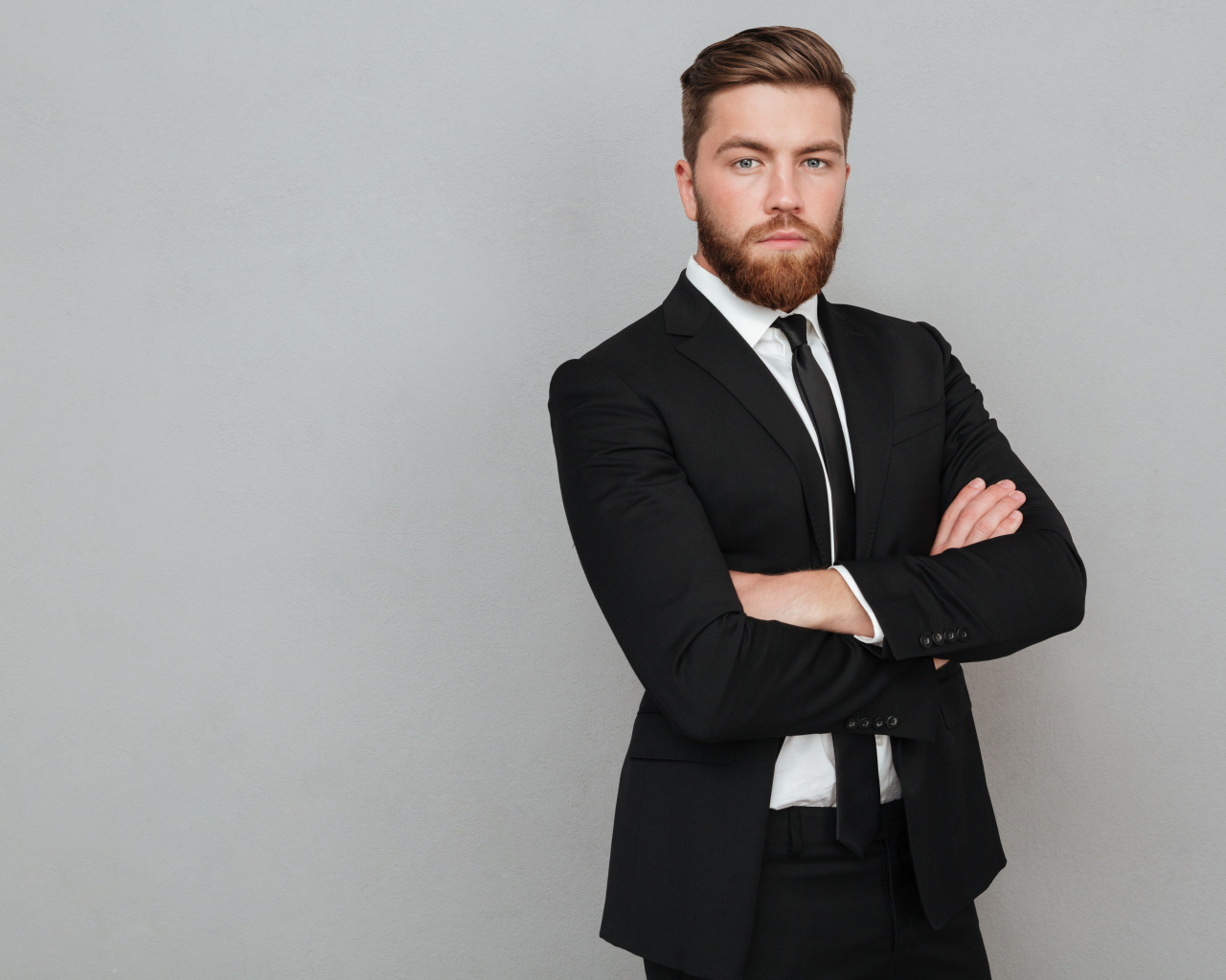 Деловой стильный мужчина в черном костюме на сером фоне