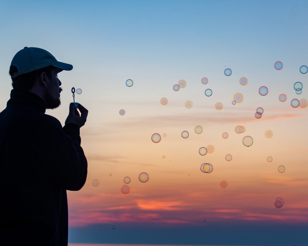 Мужчина пускает мыльные пузыри на закате