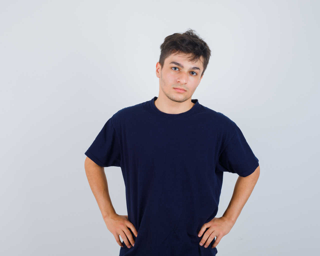 Молодой парень в синей футболке на сером фоне