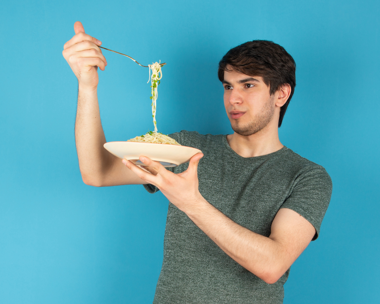Молодой человек держит тарелку со спагетти в руках