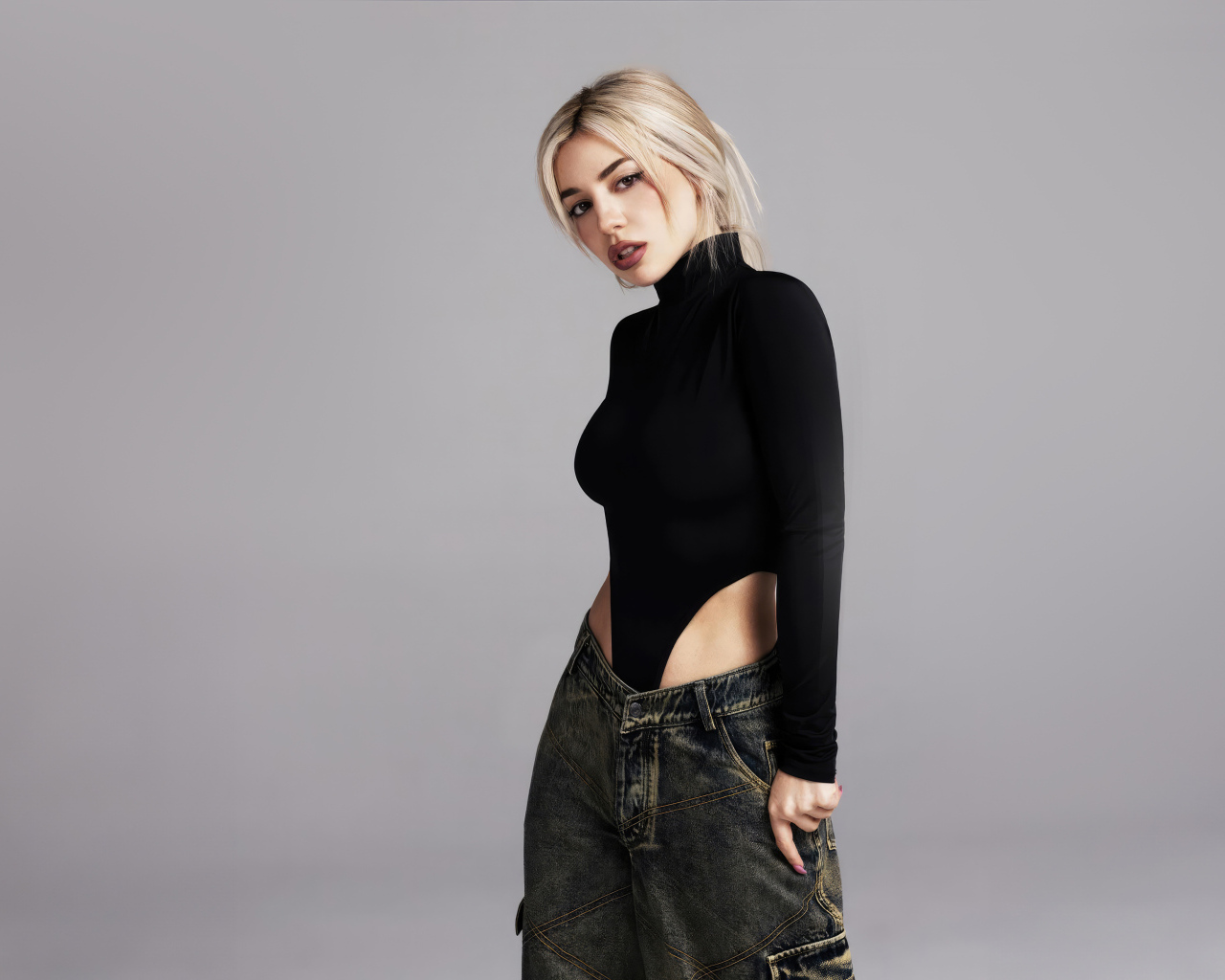 Милая блондинка певица  Эйва Макс на сером фоне