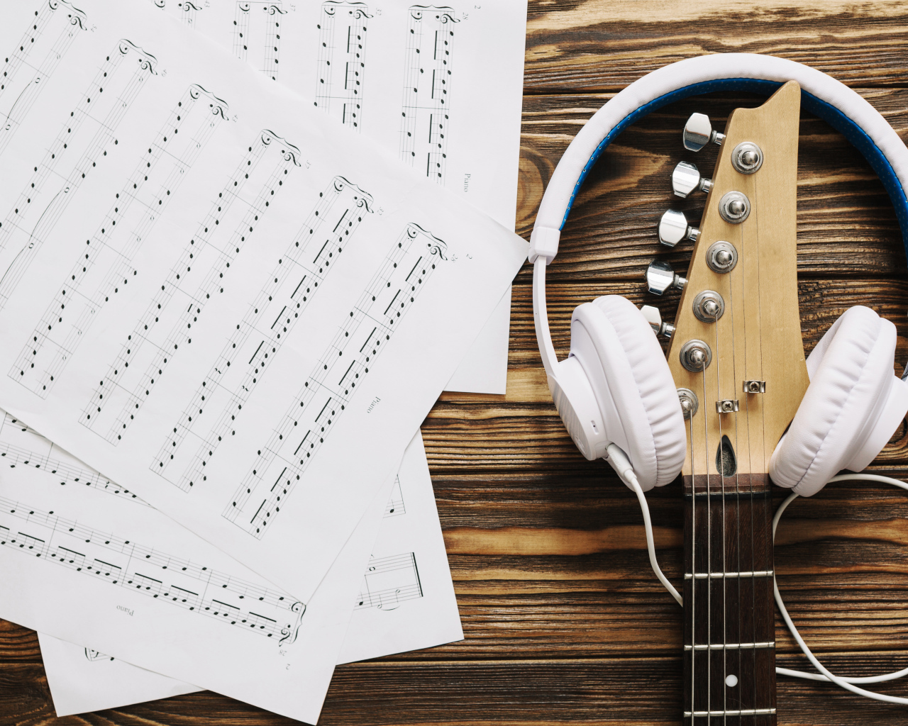 Ноты, наушники и гитара на столе