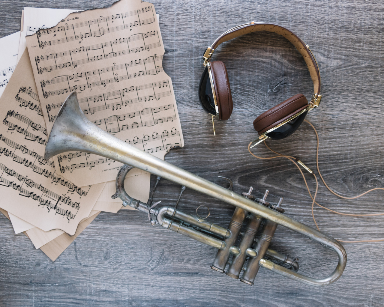 Старые ноты, наушники и труба на столе