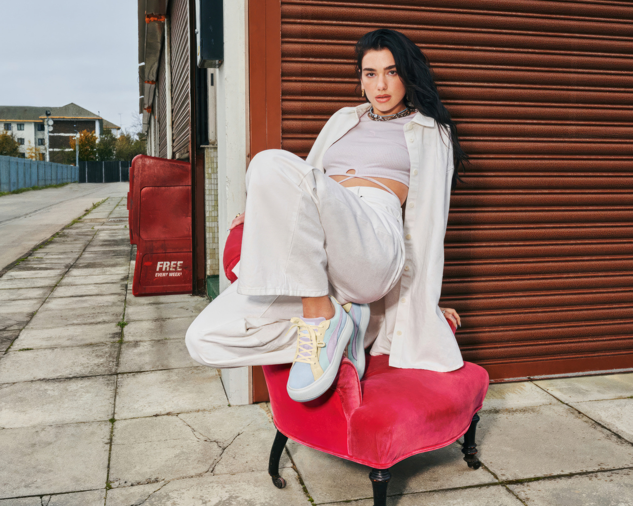 Певица Дуа Липа в белом костюме на кресле у стены