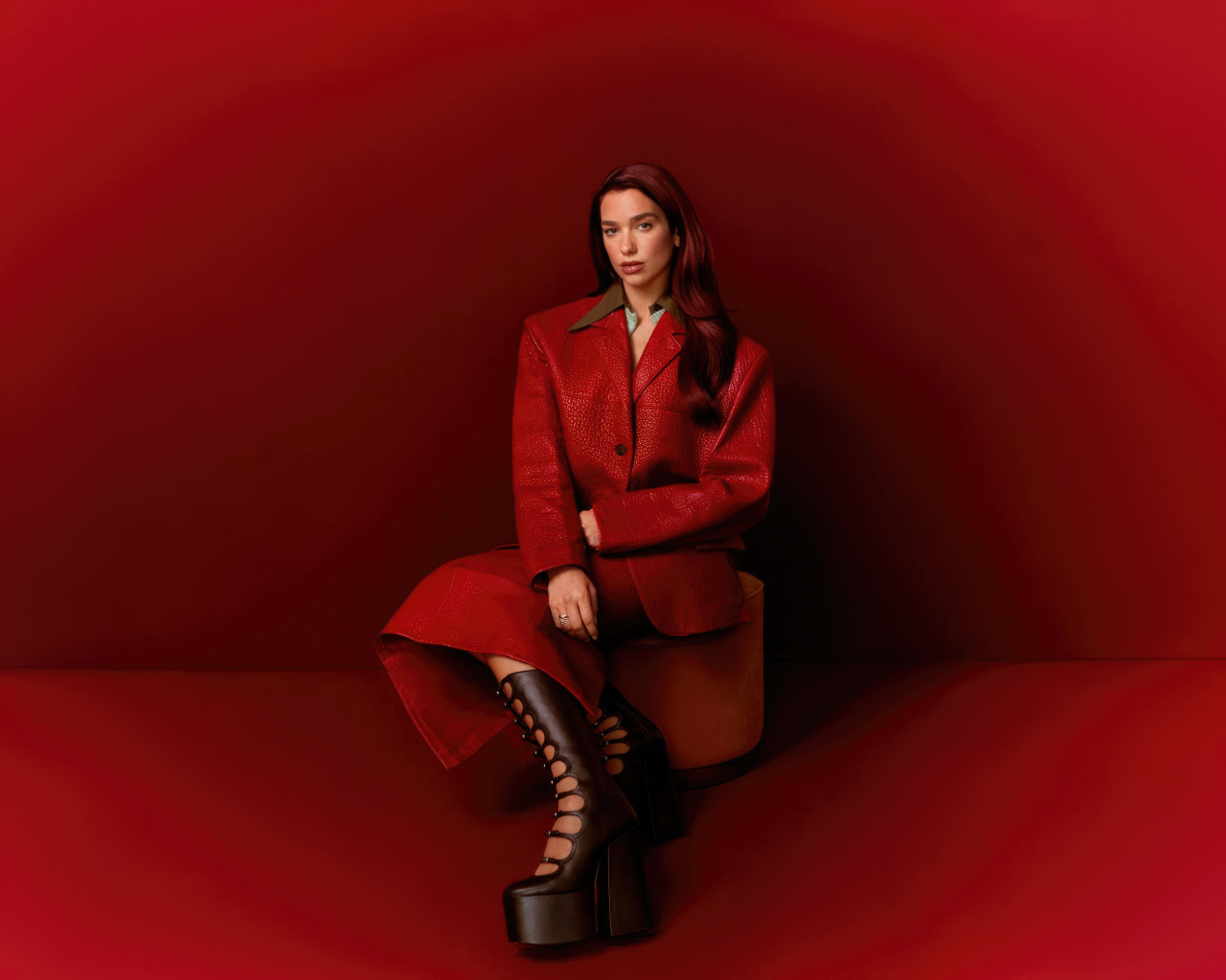 Певица Дуа Липа позирует на красном фоне