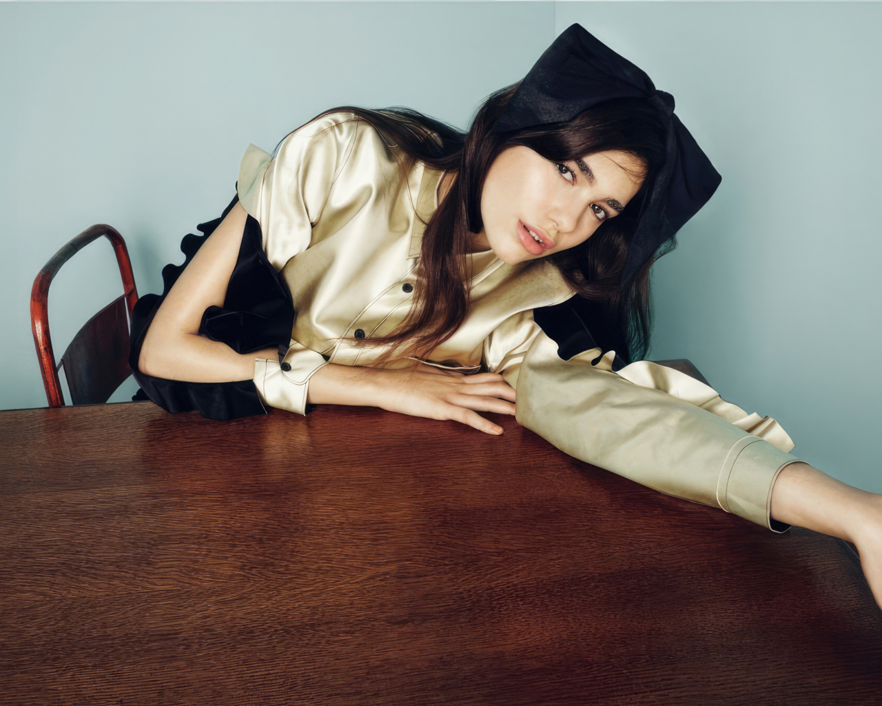 Певица Дуа Липа сидит за деревянным столом