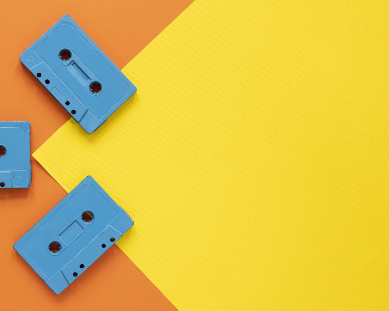 Три голубые кассеты на желто-оранжевом фоне