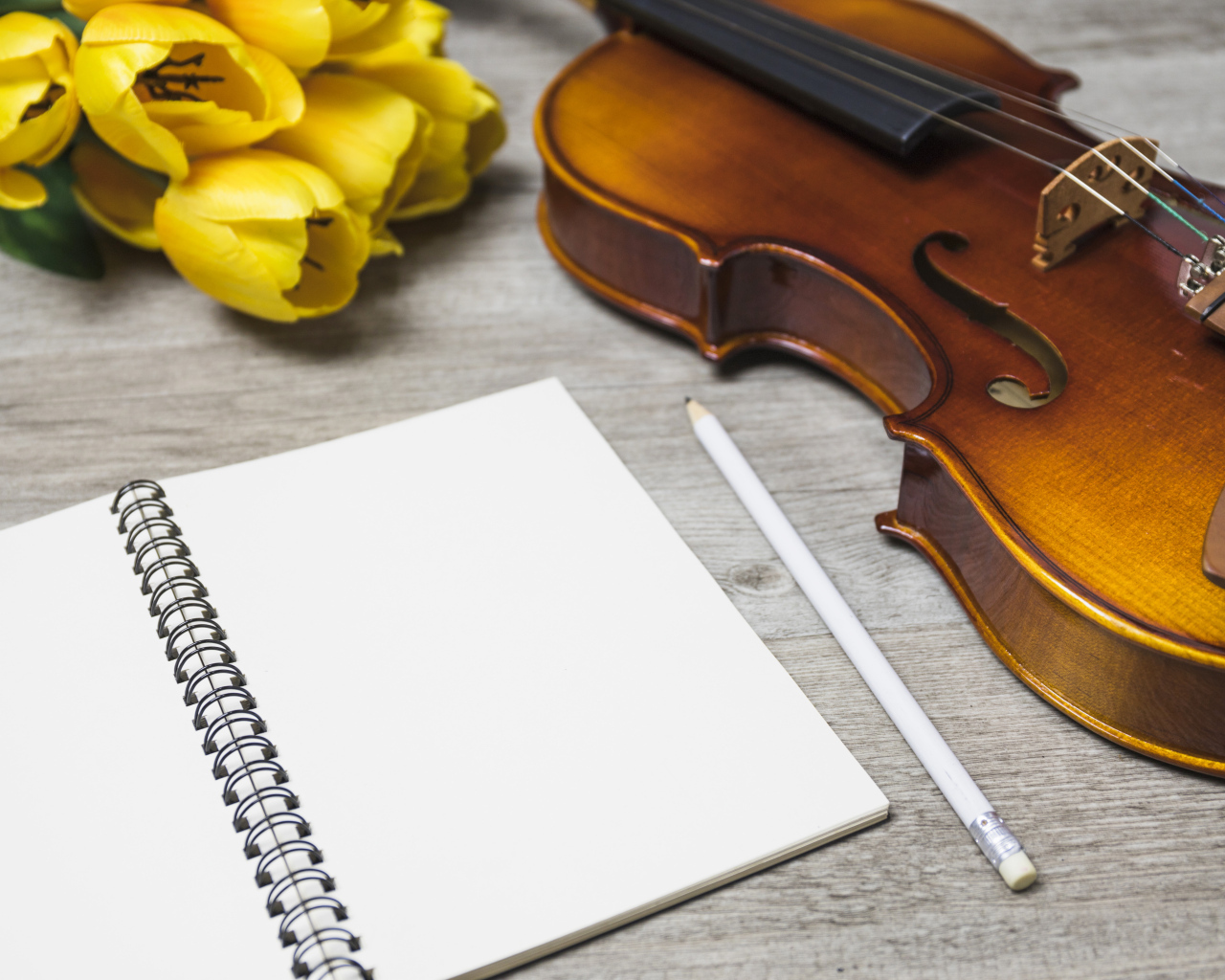 Скрипка, блокнот и желтые тюльпаны на столе