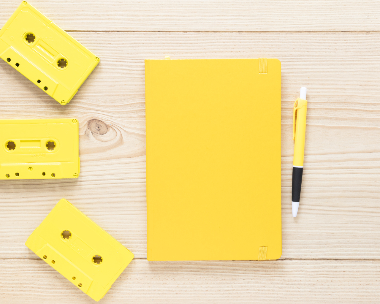 Желтый блокнот с ручкой и кассетами на столе