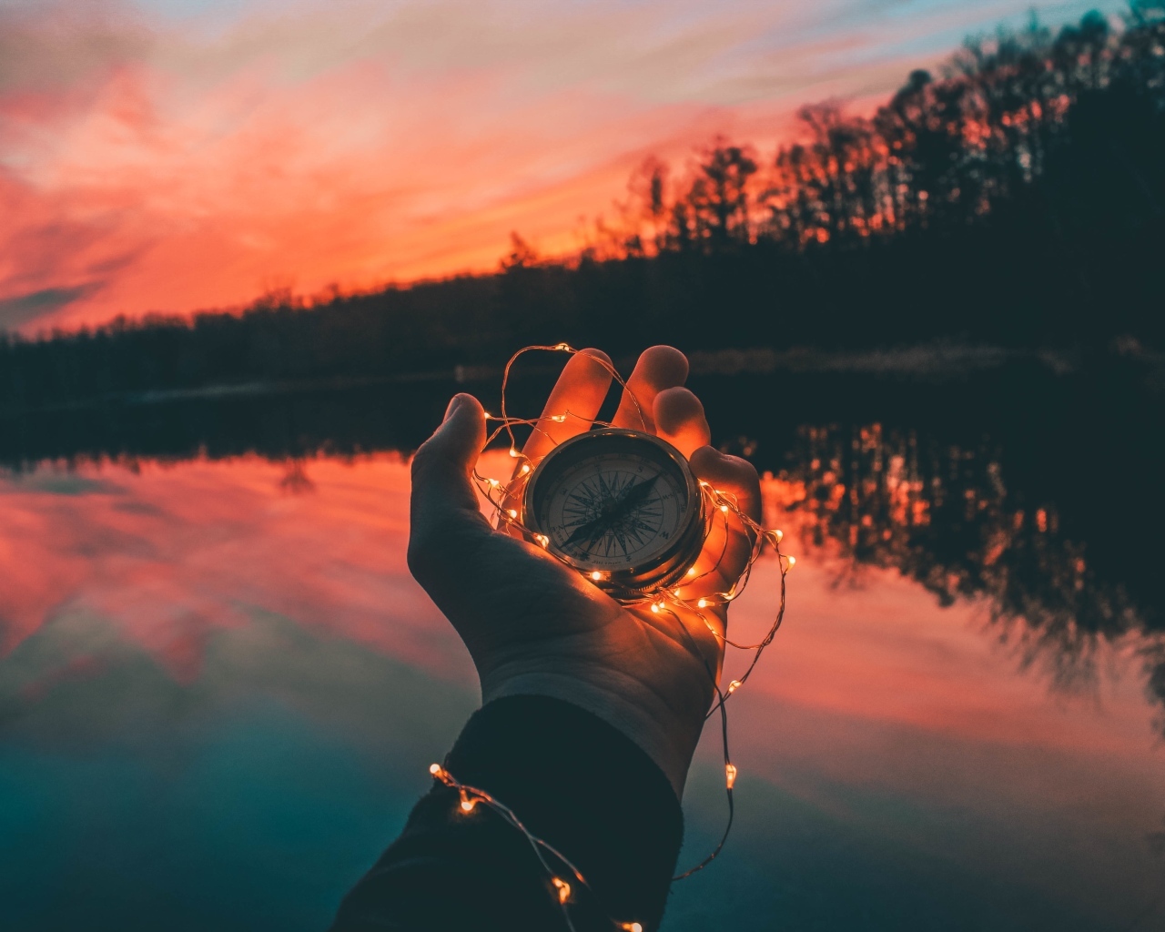 Компас с гирляндой в руке у реки