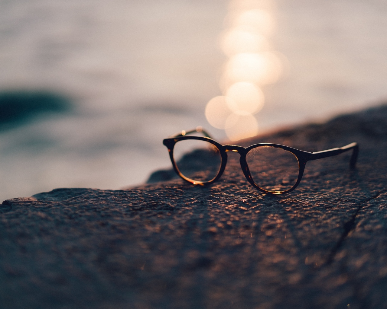 Очки лежат на камне в лучах солнца