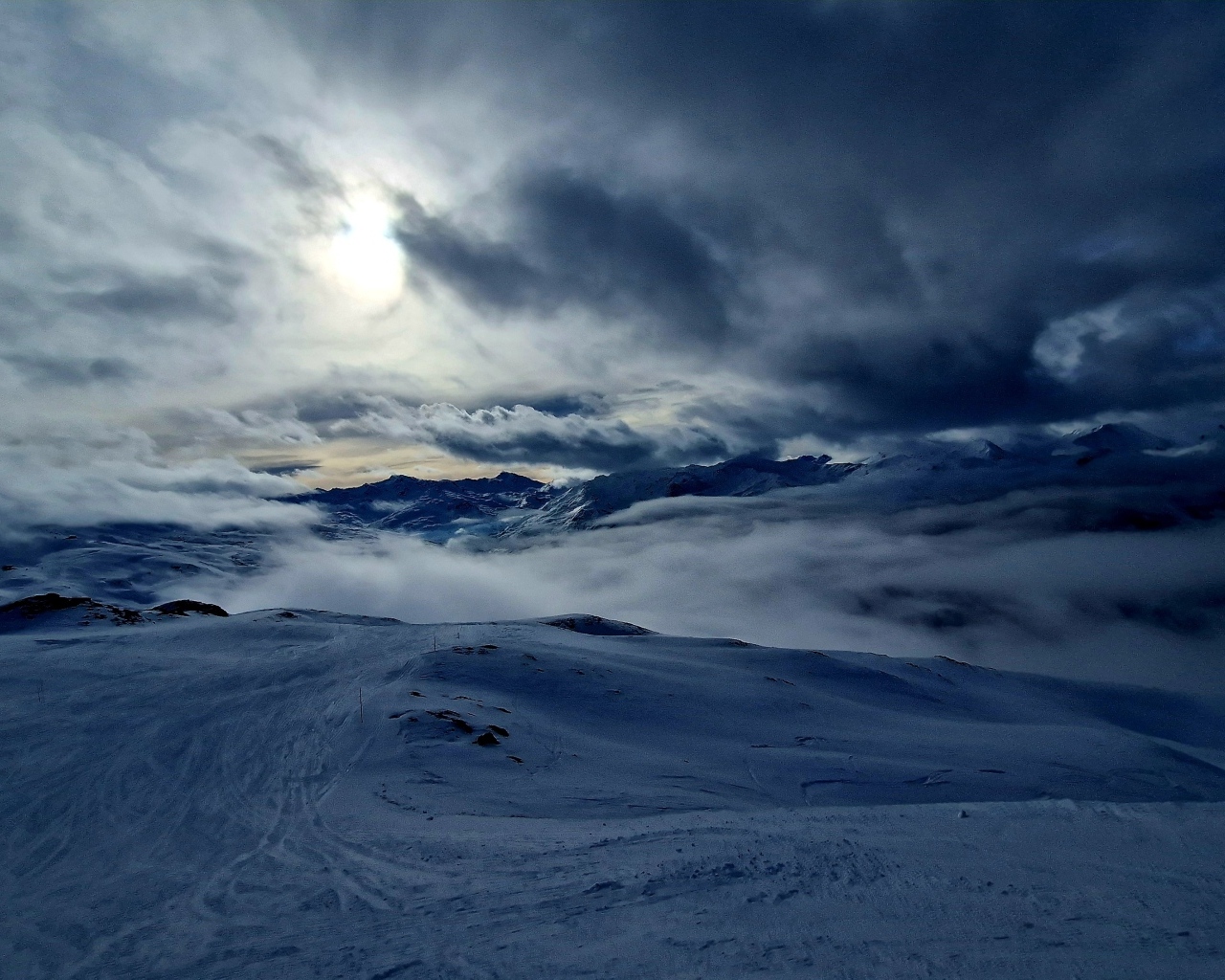 Луна в облачном небе над заснеженными горами