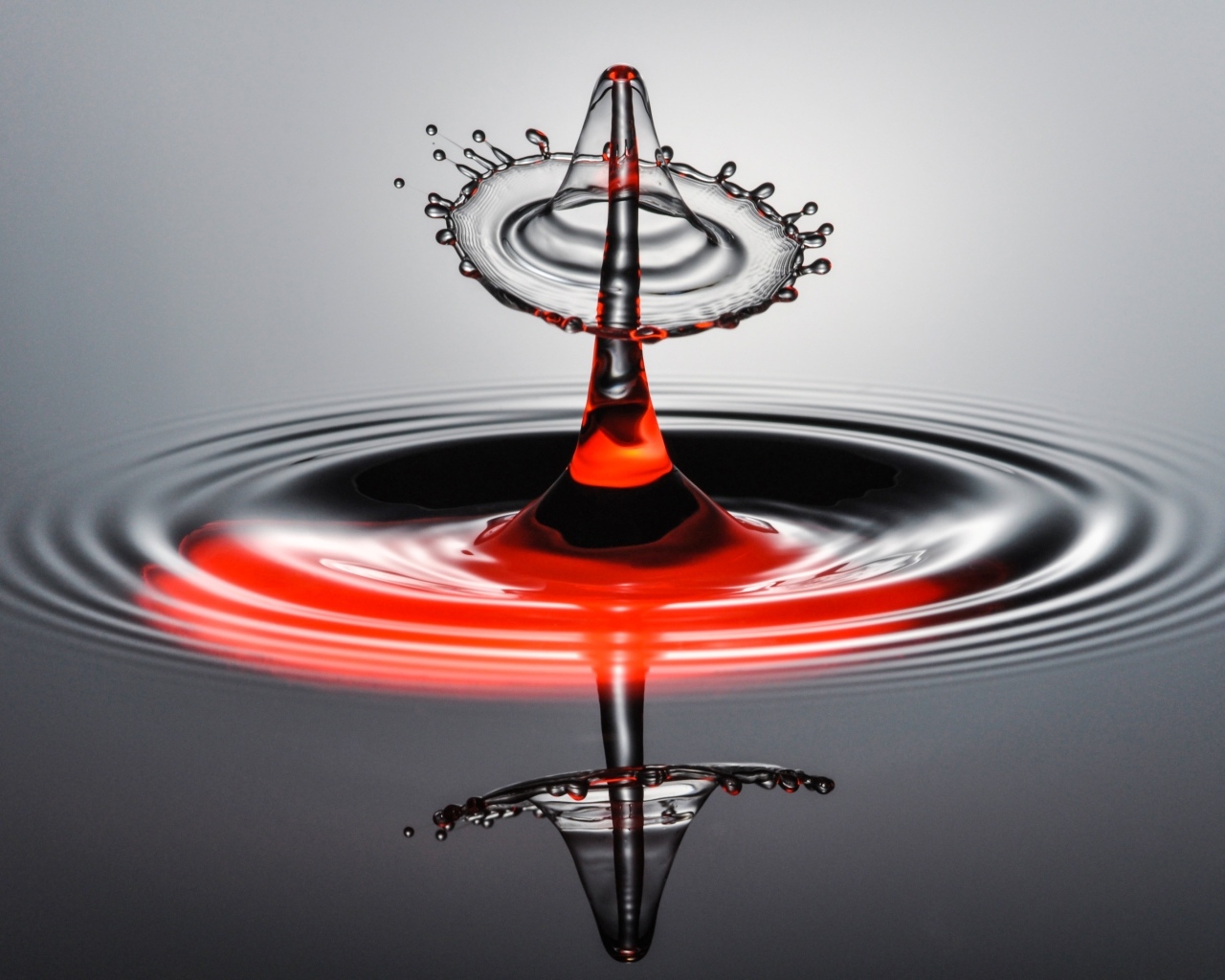 Брызги от капли воды на серой поверхности