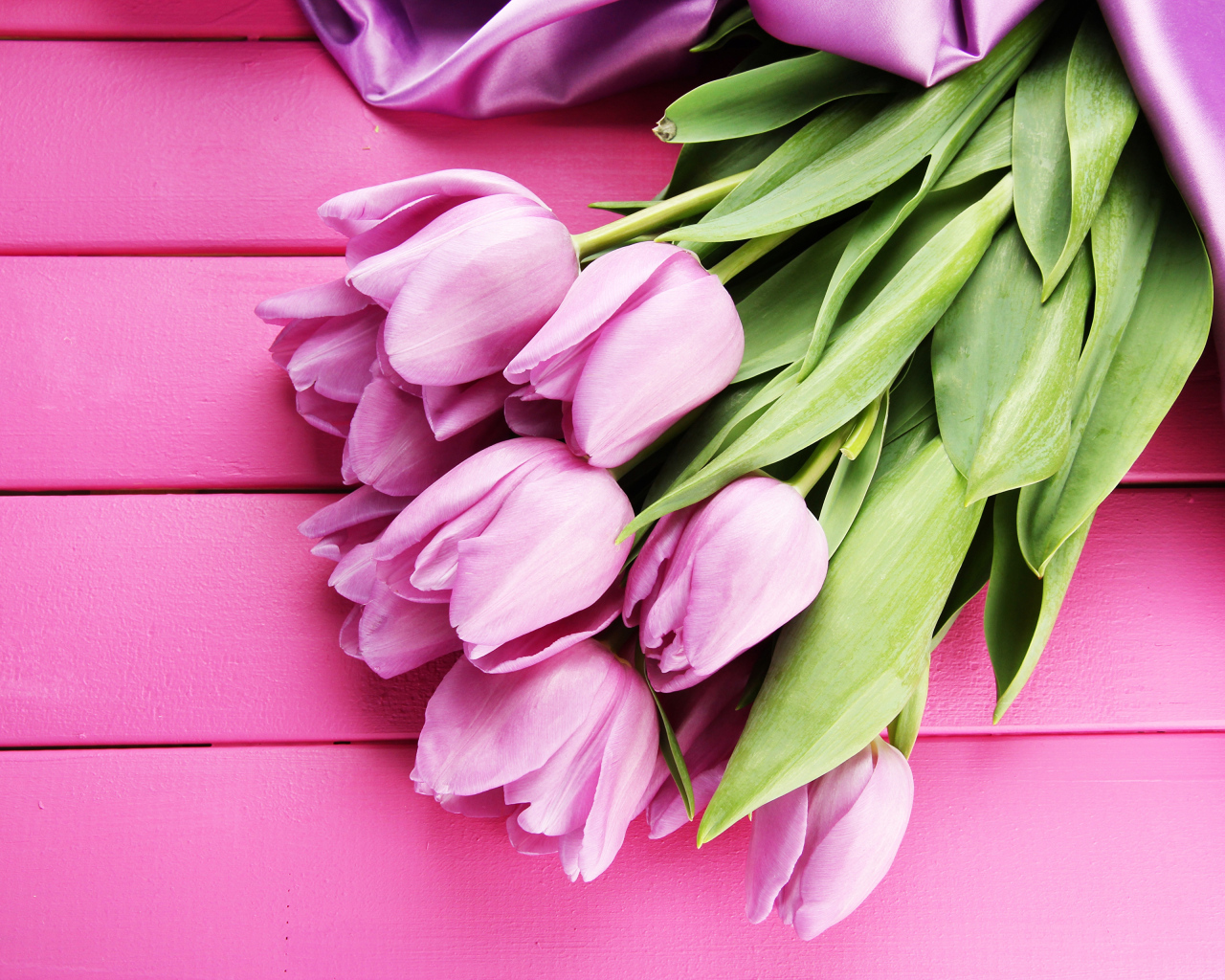 Красивый букет тюльпанов с лентой на розовом столе