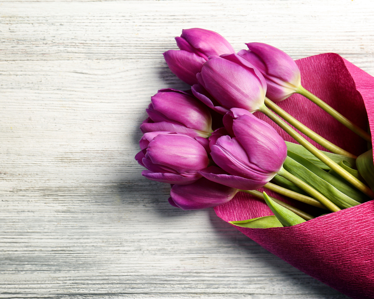 Букет сиреневых тюльпанов в бумаге на столе